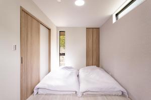 - une chambre avec un lit doté de draps blancs et une fenêtre dans l'établissement Hakone Ashinoko Lakeside Resort - 箱根芦ノ湖レイクサイドリゾート, à Hakone