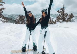 twee vrouwen op ski's in de sneeuw met hun handen in de lucht bij Greenhouse Living Apartment Fagus mit Terrasse und Feuerstelle - 7 Minuten nach Winterberg - 4 Minuten zur Ruhrquelle in Medebach