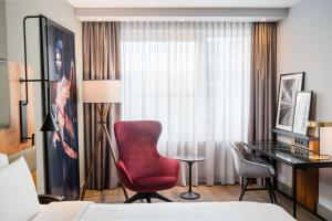 ein Hotelzimmer mit einem roten Stuhl und einem Schreibtisch in der Unterkunft Radisson Blu Hotel, Hamburg Airport in Hamburg