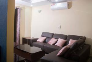 uma sala de estar com um sofá castanho e almofadas cor-de-rosa em Kadoued Furnished Apartment 2 Bedroom em Ouagadougou