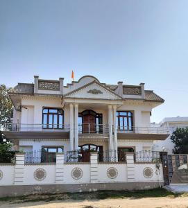 une grande maison blanche avec une clôture devant elle dans l'établissement Shree Nanda Guest House, à Varanasi