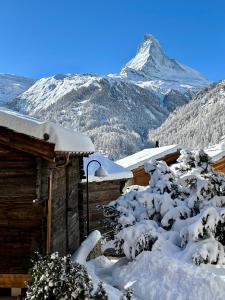 eine schneebedeckte Hütte mit einem Berg im Hintergrund in der Unterkunft Chalet Coral und Zermatter Stadel mit Sauna in Zermatt