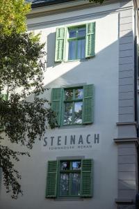 Steinach Townhouse Meran في ميرانو: مبنى أبيض عليه مصاريع خضراء