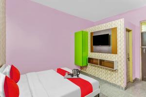 a bedroom with a bed and a tv on a wall at Hotel O K D Guest House in Manesar