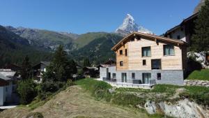 ein Haus auf einem Hügel mit einem Berg im Hintergrund in der Unterkunft Chalet Coral und Zermatter Stadel mit Sauna in Zermatt