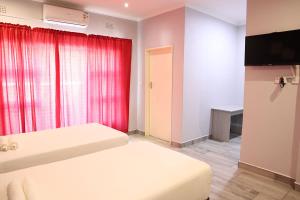 a bedroom with two beds and a red curtain at Amariah Lodge in Kasane