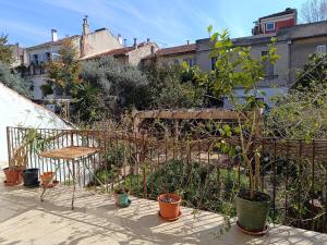 Chambre d'hôtes 2 pers - Maison avec jardin et terrasse près de la Friche de la Belle de mai في مارسيليا: حديقة فيها خزاف ونباتات ومقاعد ومباني