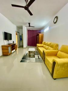 uma sala de estar com um sofá amarelo e uma televisão em 2 BHK AC Apartment em Pune