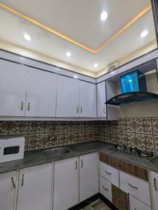 a kitchen with white cabinets and a stove at Palm View Residences in Gujrānwāla