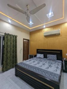 a bedroom with a bed and a ceiling fan at Palm View Residences in Gujrānwāla