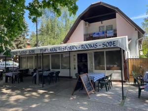 un ristorante con tavoli e sedie di fronte a un edificio di Feher Akac Guest House a Palić