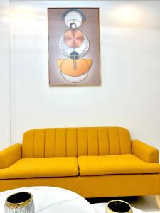 eine gelbe Couch in einem Wohnzimmer mit Bild in der Unterkunft Appartement au Almadies( piscine et salle de sport) in Dakar