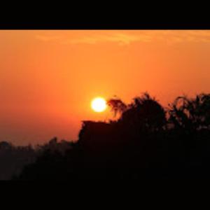 una puesta de sol naranja con el sol en el cielo en Strawberry County, en Panchgani