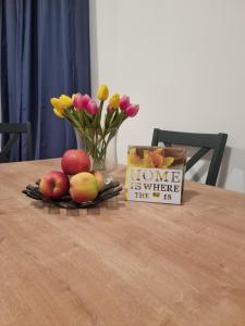 une table avec des pommes et des fleurs et un vase avec un signe dans l'établissement Dubrovnik Airport Apartment Pascal, à Močići