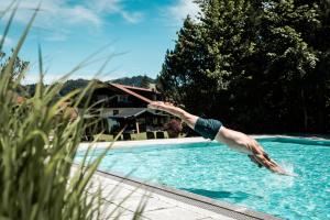 Um homem está a saltar para uma piscina. em Alpin & Wellness Resort Hotel Ludwig Royal em Oberstaufen