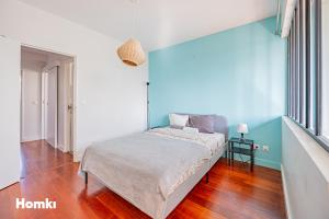 een bed in een kamer met een blauwe muur bij Beau T3-résidence calme-proche Paris/La Défense in Suresnes