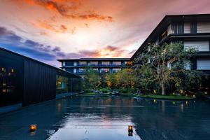 une piscine en face d'un bâtiment avec un coucher de soleil dans l'établissement HOTEL THE MITSUI KYOTO, a Luxury Collection Hotel & Spa, à Kyoto