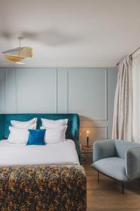 a bedroom with a bed and a blue chair at Hôtel Singulier Bordeaux - Boutique Hôtel & Spa Anne Semonin in Bordeaux