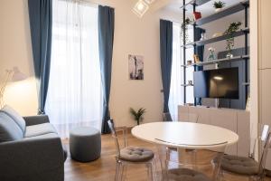 een woonkamer met een tafel, een bank en een tv bij EVE Home Collection - City Center in Trieste