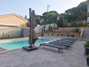 a pool with a bunch of lounge chairs and an umbrella at Edith et Jean-Paul in Porto-Vecchio