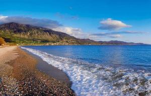 une plage avec l'océan et les montagnes en arrière-plan dans l'établissement Kalamata's Handmade Apartment, à Kalamata