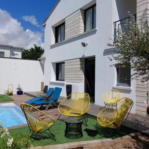 a patio with chairs and a pool in front of a house at Maison familiale avec jacuzzi et piscine in La Rochelle