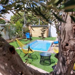 a backyard with a pool and chairs and a tree at Maison familiale avec jacuzzi et piscine in La Rochelle