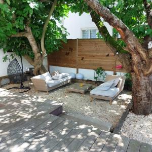 a patio with two couches and a table under a tree at Maison familiale avec jacuzzi et piscine in La Rochelle