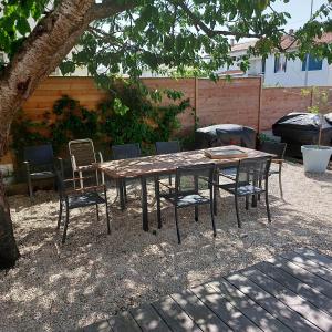 a wooden table and chairs under a tree at Maison familiale avec jacuzzi et piscine in La Rochelle