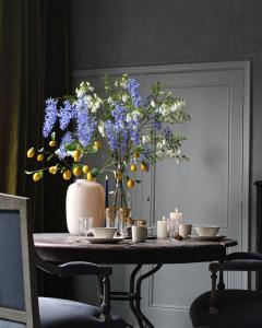 uma mesa com um vaso com flores azuis em Logies aan de Dam em Middelburg