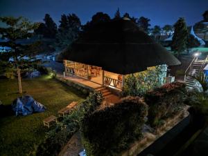 um gazebo com telhado de relva à noite em Oslo Gardens Bed & Breakfast em Entebbe