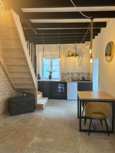 uma cozinha e sala de jantar com uma mesa e escadas em La maison de pierres em Chablis