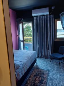 een slaapkamer met een bed, een stoel en een raam bij ninna palatin in Haifa