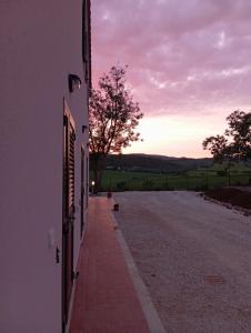 een lege weg naast een gebouw met de zonsondergang op de achtergrond bij Agriturismo Maremma Amara in Saturnia