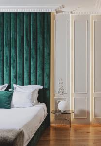 a bedroom with a green wall with a bed and a table at Hôtel Singulier Bordeaux - Boutique Hôtel & Spa Anne Semonin in Bordeaux