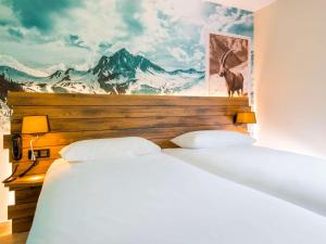 two beds in a room with a painting on the wall at Ibis Styles Sallanches Pays du Mont-Blanc in Sallanches