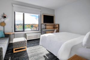 レンタムにあるTownePlace Suites By Marriott Wrentham Plainvilleのベッドと大きな窓が備わるホテルルームです。