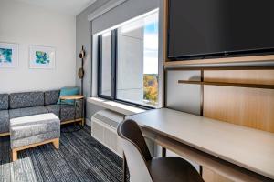 レンタムにあるTownePlace Suites By Marriott Wrentham Plainvilleのソファ、テーブル、テレビが備わる客室です。