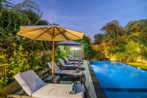 eine Gruppe von Stühlen und einem Sonnenschirm neben einem Pool in der Unterkunft The Parnas in Nusa Lembongan