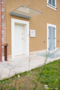 un edificio con una puerta blanca y dos ventanas en TENUTA FOGLIANI Resort & Natural Spa, en Visciano