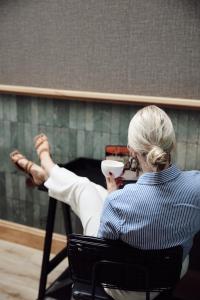 a woman sitting in a chair with a cup of coffee at Hotel Botanique Breda in Breda