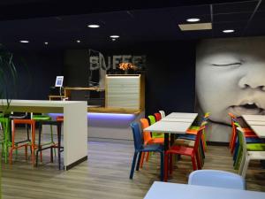 un restaurante con mesas y sillas y una gran cara en la pared en ibis budget Cholet Centre, en Cholet