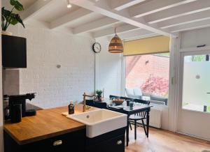 a kitchen with a sink and a table with chairs at Bos Water Huisje Veluwemeer in Biddinghuizen