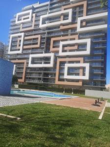 um grande edifício de apartamentos com um campo de relva em frente em Rocha T Apartments em Portimão