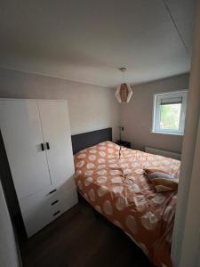 a bedroom with a bed and a white cabinet at 4 tot 8 persoons huisje - Veluwemeer - Biddinghuizen - Harderwijk - Elburg in Biddinghuizen