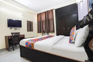 una camera con letto, scrivania e TV di FabExpress IVY Inn Sector 35 a Noida