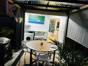 een patio met een tafel en stoelen en een keuken bij 2Bays Studio- Walk to 2 Beaches! Perfect Location with Private Courtyard & BBQ in Nelson Bay