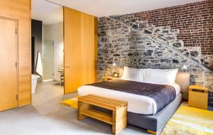 1 dormitorio con cama y pared de ladrillo en Hotel Gault, en Montreal