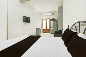 1 dormitorio con 1 cama blanca y 1 silla en Hotel O Pravin Guest House, en Goa