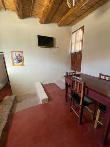 a room with a table and a tv on a wall at Bello Atardecer in Tilcara